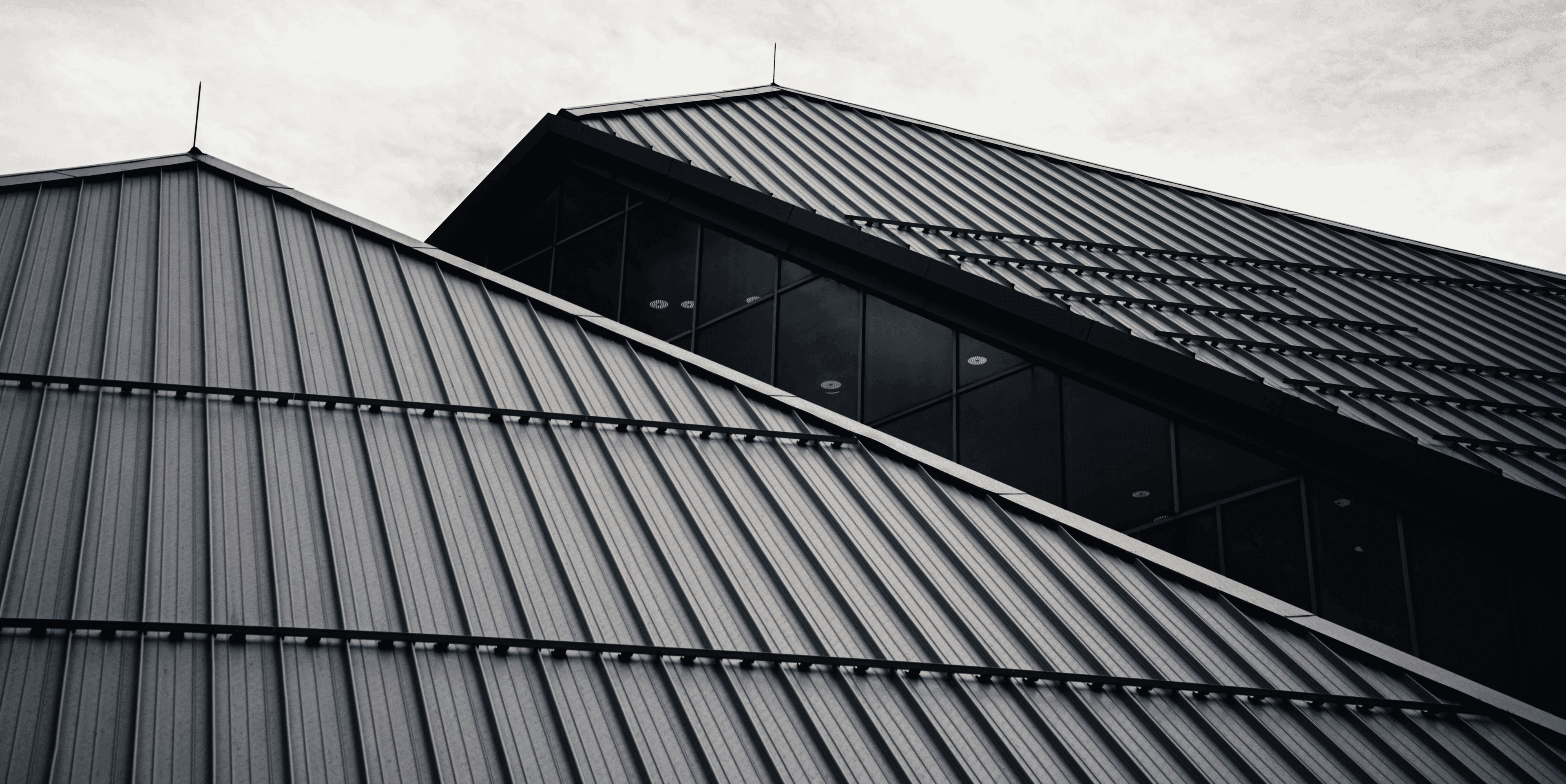 A metal roof photographed from below against an overcast sky.
